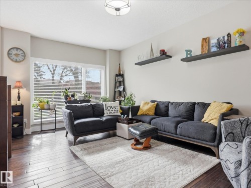 Spacious living area featuring expansive windows with horizontal blinds, wood-finish flooring, light-toned walls, and ceiling-mounted lighting - 12820 68 Street, Edmonton, AB - Indoor Photo Showing Living Room