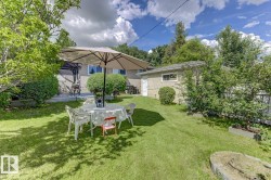 Expansive backyard featuring a manicured lawn, established perimeter trees, and a detached structure with a pitched roof - 