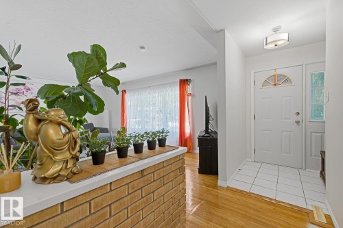 Entryway featuring a white paneled door with an arched glass insert, a coordinating sidelight, and a ceiling-mounted light fixture - 15707 92 Avenue, Edmonton, AB 