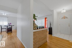Entryway featuring a paneled door with an arched glass insert, white square floor tiles, and a contemporary ceiling light fixture - 