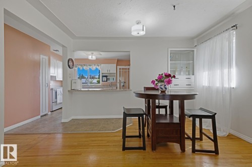 Hardwood flooring extends through the dining area, featuring a built-in display cabinet and a large window - 15707 92 Avenue, Edmonton, AB 