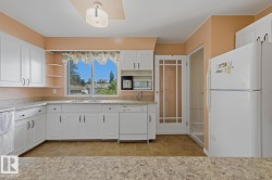 Kitchen featuring an L-shaped counter configuration with white cabinetry, a double basin sink, and wood-finish flooring - 