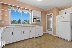 Kitchen featuring white cabinetry, light-toned countertops, a large window, tile-finish flooring, and a glass-paneled door - 
