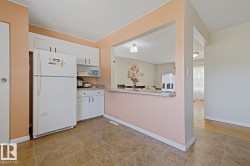 Kitchen featuring white cabinetry, granite-finish countertops, and a pass-through window with a breakfast bar - 