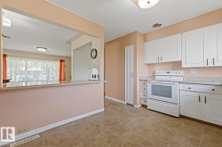 Kitchen featuring white cabinetry, light-toned countertops, a white electric range, and tiled flooring - 