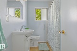 Bathroom featuring a white vanity with integrated sink, chrome faucet, wall-mounted mirror, and a window for natural light - 
