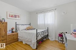 Light-filled room featuring wood-finish flooring, neutral wall tones, and a window with sheer white curtains - 