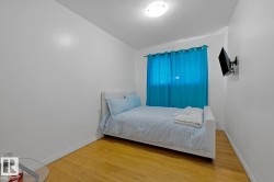 Room featuring wood-finish flooring, white walls, and a window with vibrant blue curtains - 