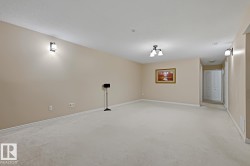 Spacious interior room featuring light-toned carpeting, neutral wall paint, and white baseboards - 