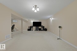 Finished lower level featuring neutral wall paint, light-colored carpet, recessed lighting, and wall-mounted sconces - 