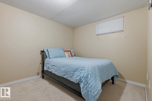 Carpeted room featuring neutral-toned walls, white trim, and a high window with blinds - 15707 92 Avenue, Edmonton, AB 