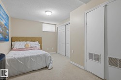 Carpeted room featuring a ceiling-mounted light fixture, a window with a roller shade, and two white bi-fold closet doors - 