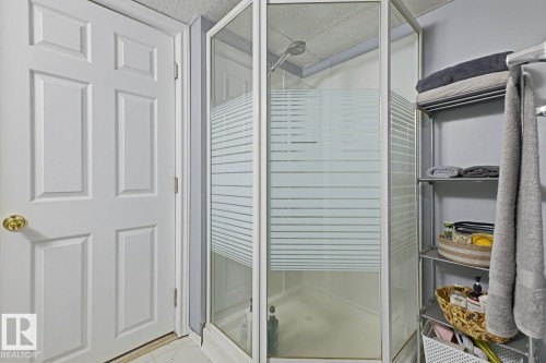Corner shower enclosure with frosted glass panels and a showerhead - 15707 92 Avenue, Edmonton, AB 