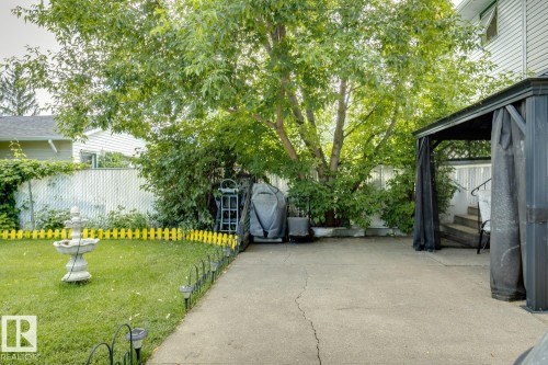 Landscaped backyard featuring a concrete patio, mature tree, and a covered gazebo structure - 3015 131 Avenue, Edmonton, AB 
