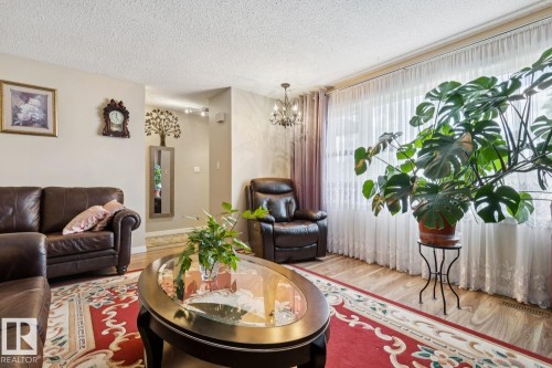 Living area featuring wood-finish flooring, neutral wall paint, and a decorative chandelier - 3015 131 Avenue, Edmonton, AB 