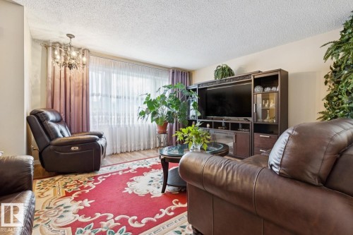 Living area featuring wood-finish flooring, a contemporary chandelier, and a built-in media console with display cabinetry - 3015 131 Avenue, Edmonton, AB 