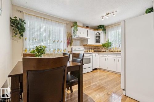 Bright kitchen featuring wood-finish flooring, white cabinetry, a white electric range, and track lighting - 3015 131 Avenue, Edmonton, AB 