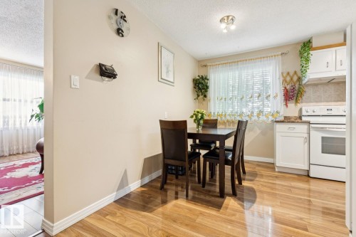 Dining area featuring wood-finish flooring, a window with horizontal blinds, and white base cabinetry with a light-colored countertop - 3015 131 Avenue, Edmonton, AB 