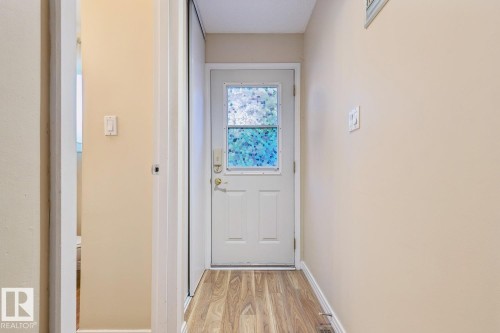 Entryway featuring a white door with frosted glass, wood-finish flooring, and neutral wall paint - 3015 131 Avenue, Edmonton, AB 