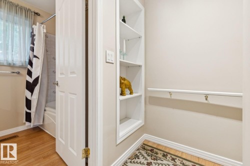 Bathroom featuring light beige walls, wood-finish flooring, and a built-in shelving unit - 3015 131 Avenue, Edmonton, AB 