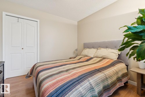 Light-toned walls complement wood-finish flooring in this room featuring a white bi-fold closet door and a textured ceiling - 3015 131 Avenue, Edmonton, AB 