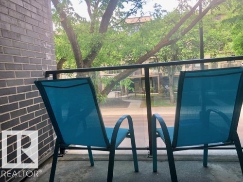 Private balcony featuring a glass and metal railing, concrete flooring, and a dark brick exterior wall - 216 11503 76 Avenue, Edmonton, AB 