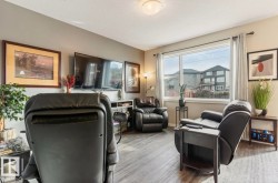 Spacious living area featuring expansive window, wood-finish flooring, neutral wall tones, and overhead lighting - 