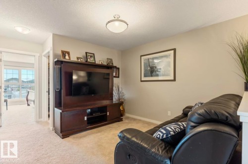 Carpeted living area featuring a built-in media console, neutral wall color, and ceiling-mounted lighting - 12737 205 Street Nw, Edmonton, AB 