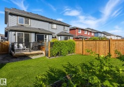 Rear exterior featuring a ground-level deck with black railing, sliding glass door, and vinyl siding - 