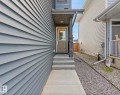 Front entry with concrete steps and landing, featuring a covered porch with a stone-accented pillar - 12737 205 Street Nw, Edmonton, AB 