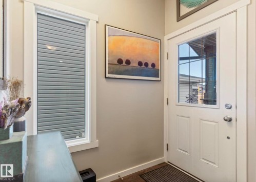 Entryway with a white paneled door featuring an upper window with internal grilles, complemented by a sidelight window with integrated blinds - 12737 205 Street Nw, Edmonton, AB 