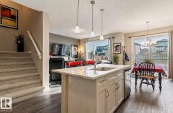 Kitchen island with an undermount double-basin sink, pendant lighting, and white cabinetry - 