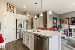 Kitchen island featuring a double basin sink, stainless steel dishwasher, and light-toned countertop - 
