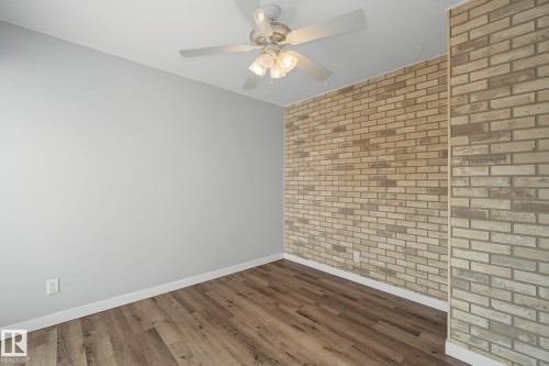 Neutral-toned interior featuring an exposed brick accent wall - 9545 65 Avenue, Edmonton, AB 