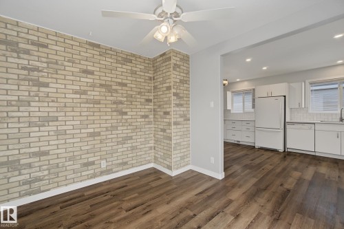 Open concept living space featuring a brick accent wall and wood-finish flooring - 9545 65 Avenue, Edmonton, AB 
