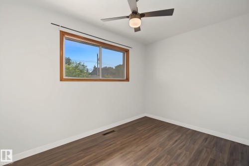 Room featuring wood-finish flooring, white baseboards, a wood-framed window, and a ceiling fan with integrated lighting - 9545 65 Avenue, Edmonton, AB 