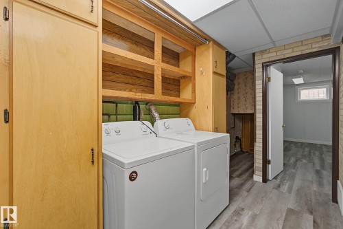 Dedicated laundry area featuring a washer and dryer, wood cabinetry, open shelving, and green tiled backsplash - 9545 65 Avenue, Edmonton, AB 