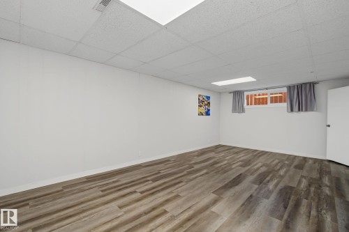 Spacious room featuring wood-finish flooring and a drop ceiling - 9545 65 Avenue, Edmonton, AB 