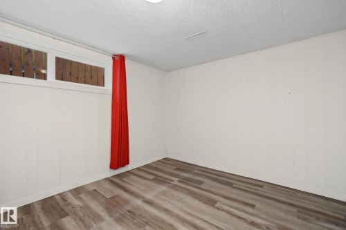 Room featuring wood-finish flooring, white paneling, and a white ceiling with recessed lighting - 9545 65 Avenue, Edmonton, AB 