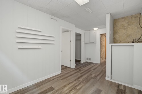 Versatile room featuring wood-finish flooring, white paneled walls, and built-in shelving - 9545 65 Avenue, Edmonton, AB 
