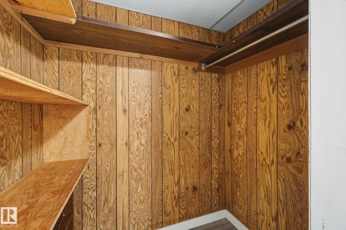 Wood-paneled closet featuring multiple built-in shelving units and a hanging rod - 9545 65 Avenue, Edmonton, AB 
