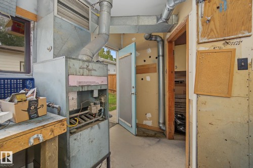 Utility room featuring a central heating unit, exposed ductwork, and a built-in workbench - 9545 65 Avenue, Edmonton, AB 