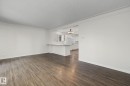 Spacious living area featuring wood-finish flooring and crown molding - 9545 65 Avenue, Edmonton, AB 