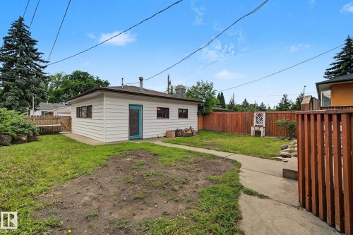 Detached rear building with a vibrant blue door, multiple windows, and a concrete perimeter - 9545 65 Avenue, Edmonton, AB 