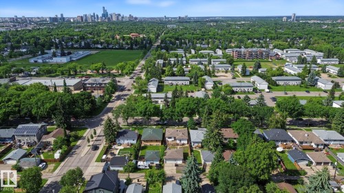Expansive residential area featuring a mix of housing styles, established tree canopy, and city skyline backdrop - 9545 65 Avenue, Edmonton, AB 