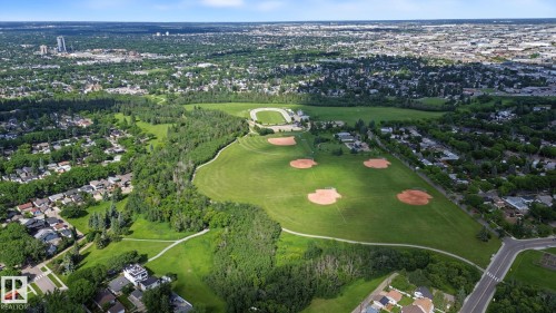 Expansive green space featuring multiple baseball diamonds, a track, and walking paths surrounded by lush trees and residential areas - 9545 65 Avenue, Edmonton, AB 