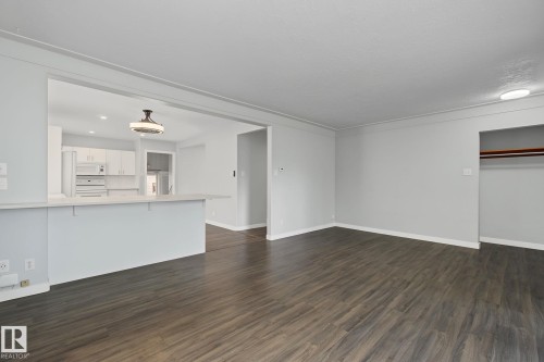Spacious living area featuring dark wood-finish flooring, light gray walls, and crown molding - 9545 65 Avenue, Edmonton, AB 