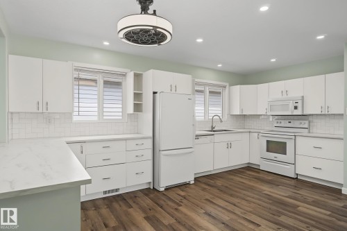 Kitchen featuring white cabinetry, light countertops, wood-finish flooring, white subway tile backsplash, and recessed lighting - 9545 65 Avenue, Edmonton, AB 
