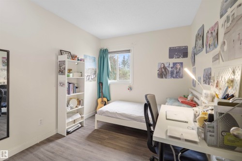 Bedroom featuring wood-finish flooring, a white trim window, and neutral wall paint - 173 Tudor Lane, Edmonton, AB 