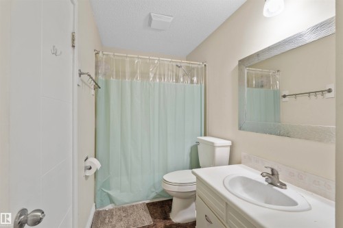 Bathroom featuring a single vanity with an integrated sink, white countertop, and a decorative framed mirror - 173 Tudor Lane, Edmonton, AB 